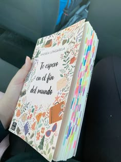 a person is holding up a book in their hand while sitting in the back seat of a car