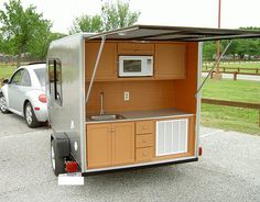 an outdoor kitchen area with a car parked in the parking lot and another vehicle behind it