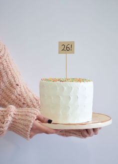 a person holding a white cake with a sign on it that says twenty two cents