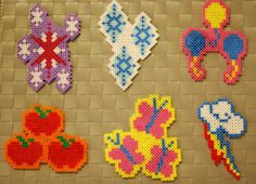 six pieces of perler bead art are arranged on a tile background, including one with an elephant, the other with flowers and hearts