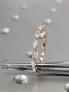 a pair of diamond wedding rings sitting on top of a metal table with screwdrivers