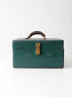 an old green metal box with a handle on the top and a worm sticking out of it