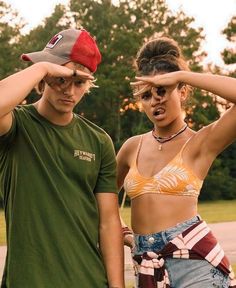 two people standing next to each other with their hands on their foreheads and one woman covering her eyes