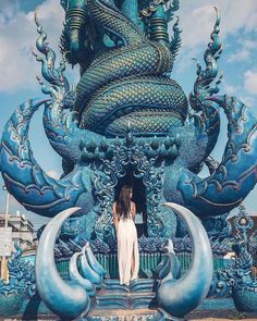 a woman standing in front of a blue dragon statue