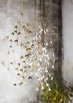 three wind chimes hanging from the ceiling in front of a brick wall and potted plant