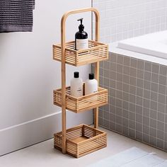 a bamboo shelf with soap and lotion on it in front of a bathtub