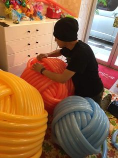 a man is working on an assortment of large, colorful hoses in a room