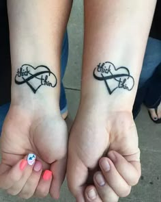 two people holding hands with tattoos on their wrists