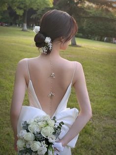 the back of a bride's dress with flowers in her hair, holding a bouquet