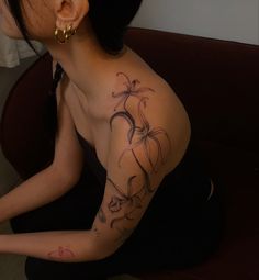 a woman is sitting on the floor with her arm and shoulder tattoo design in black ink