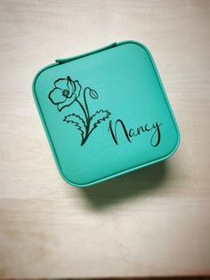 a mint green lunch box with flowers and the word money written on it in cursive writing