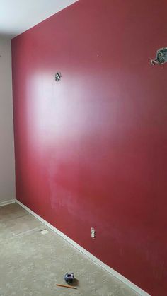 an empty room with red walls and tools on the floor