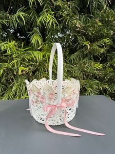 a small white basket with pink ribbon on top