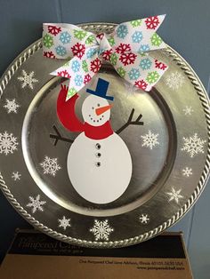 a metal plate with a snowman on it and a ribbon tied around the edge