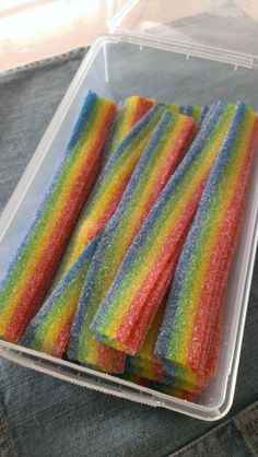 there are rainbow colored candy sticks in the plastic container