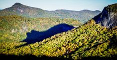 the mountains are covered in green and yellow foliage, with shadows from trees on them