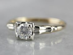 a close up view of an engagement ring with a diamond in the center, on a gray surface