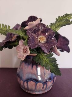 purple flowers in a blue vase with green leaves