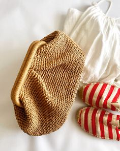 a pair of red and white striped shoes next to a straw purse on a bed