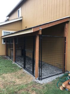 a dog kennel in front of a house with a fence around it and an open door on the side