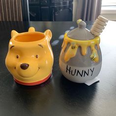 two winnie the pooh cups sitting on top of a table