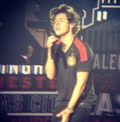 a young man standing on top of a stage with his hand up to his mouth