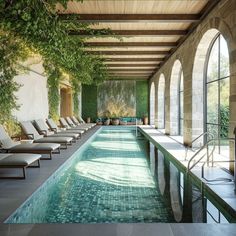 an indoor swimming pool surrounded by lounge chairs