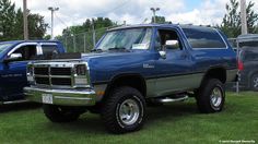 two large trucks parked next to each other in the grass