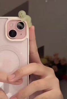 a person holding up a pink phone case with a small toy on top of it