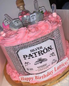 a birthday cake with pink frosting and silver patron bottles on it's top