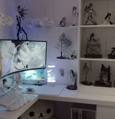 a desk with a computer on it and many figurines in the back ground