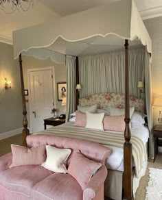 a bedroom with a canopy bed, pink couch and chandelier