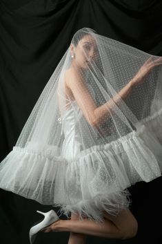 a woman in white dress and veil posing for the camera with her hands on her hips