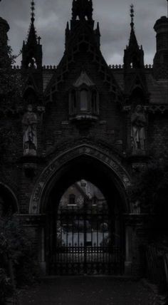 an old building with a gate in front of it on a cloudy day at night