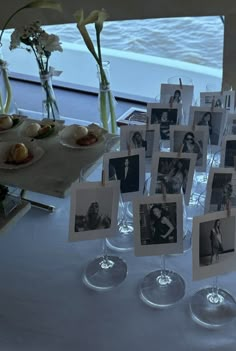 an arrangement of photos and wine glasses on a table with flowers in vases next to them