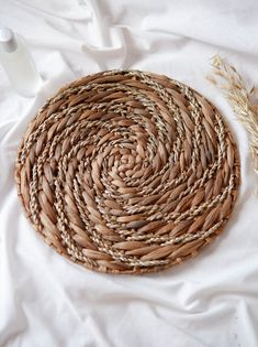 a round woven basket sitting on top of a bed next to a bottle of water