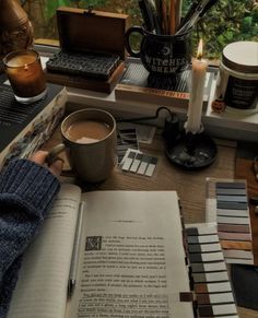 a person sitting at a desk with a book and coffee cup