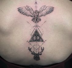 a woman's back with an owl and triangle tattoo on it