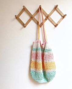 a crocheted bag hanging from a hook on a wall next to a coat rack