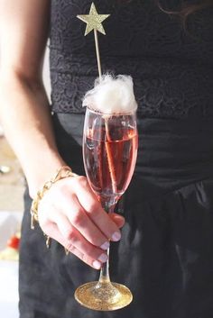 a close up of a person holding a wine glass filled with liquid and topped with a star