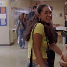 a woman is shaking hands with a man in a hallway full of other people and smiling