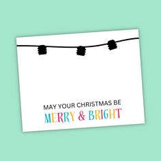 a merry and bright christmas card hanging from a line with lights in the sky above it