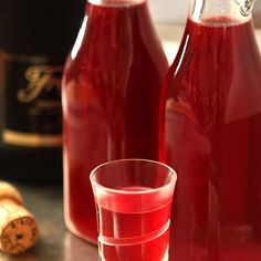 two bottles and a glass filled with red liquid