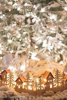 a close up of a christmas tree with lights in the middle and houses on it