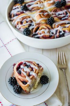 a plate with a pastry on it next to a bowl of berries and a fork