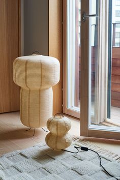 a lamp sitting on top of a rug in front of a window next to a door