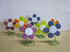 four colorful glass flowers sitting on top of each other in front of a white wall