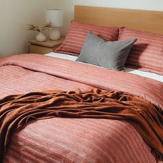 the bed is made up with red and gray striped sheets, pillows, and blankets