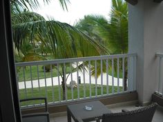 a balcony with two chairs and a table next to palm trees on the side walk