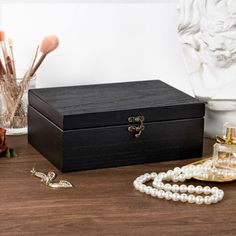 a wooden box with pearls and other accessories on a table next to a busturine